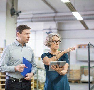 A Man Holding Paperwork and a Woman Holding a Tablet Whilst Talking